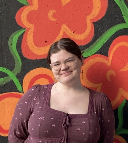 Madeline smiling in front of a floral mural